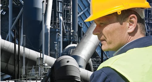 Stern looking worker in front of an imposing factory of a heavy industry facility